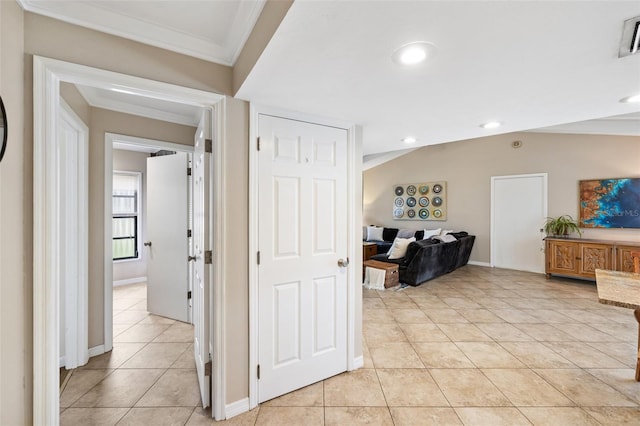 hallway featuring crown molding, lofted ceiling, and light tile patterned flooring