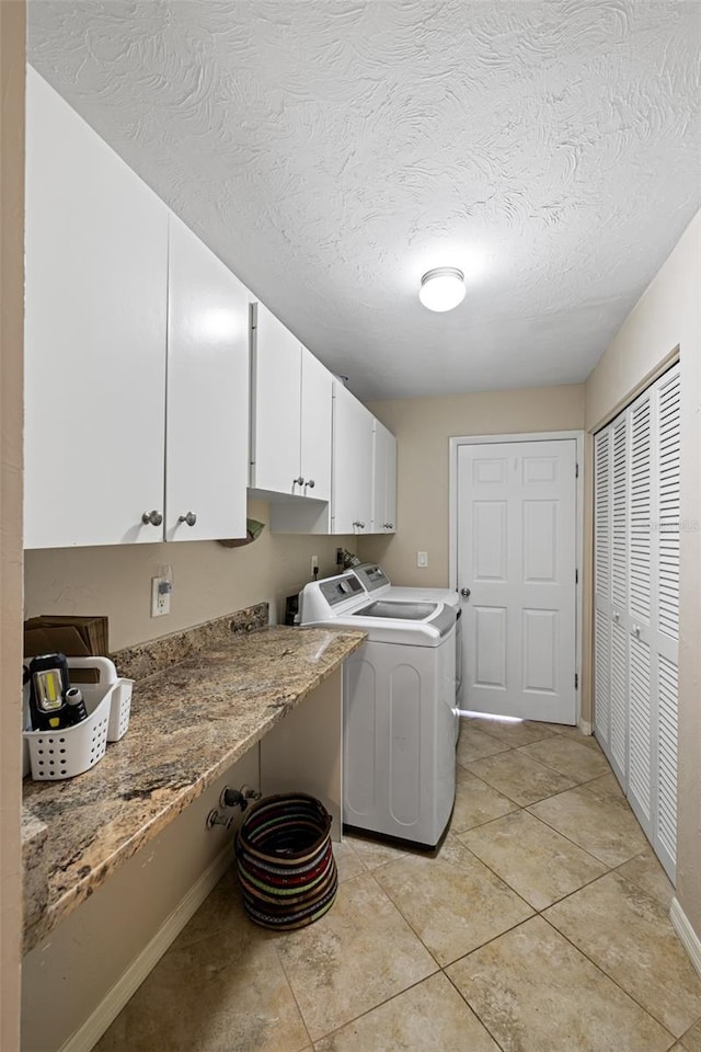 laundry room with separate washer and dryer, light tile patterned floors, cabinets, and a textured ceiling