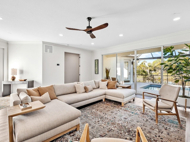 living room featuring hardwood / wood-style flooring, ornamental molding, and ceiling fan