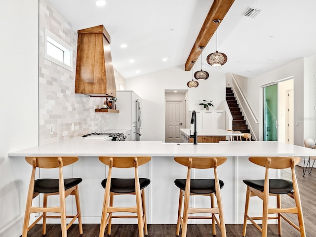 kitchen featuring dark wood-type flooring, stove, custom range hood, decorative backsplash, and kitchen peninsula