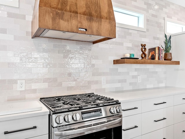 kitchen featuring gas range, tasteful backsplash, custom exhaust hood, and white cabinets