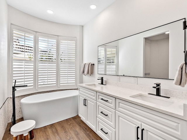 bathroom with vanity, hardwood / wood-style floors, and a washtub