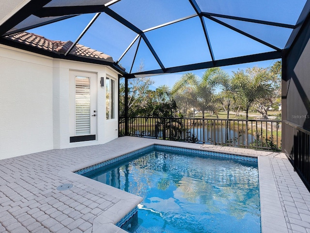 view of swimming pool with a lanai, a patio area, and a water view