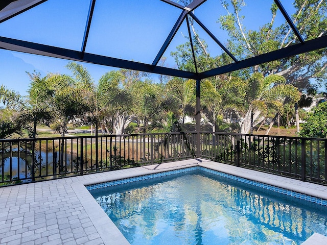 view of pool with a water view and glass enclosure