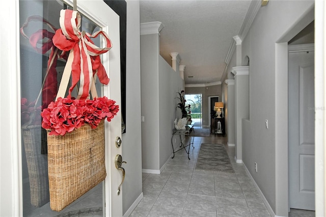 entryway with light tile patterned floors and crown molding