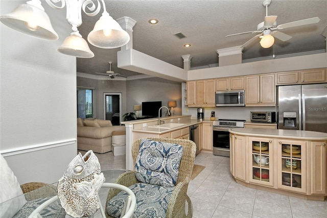 kitchen with sink, stainless steel appliances, kitchen peninsula, decorative light fixtures, and light brown cabinetry