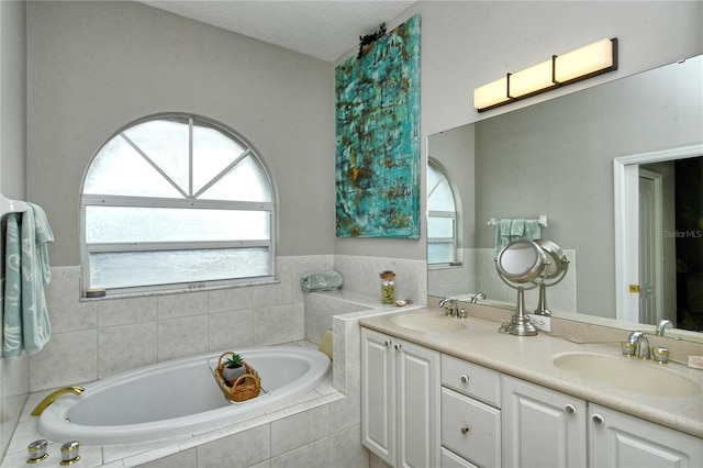 bathroom with tiled tub and vanity