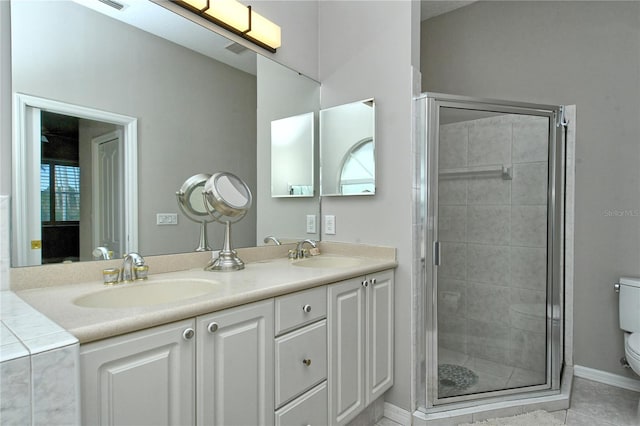 bathroom featuring tile patterned floors, vanity, toilet, and a shower with door