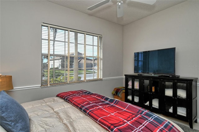 bedroom featuring ceiling fan, a textured ceiling, and multiple windows