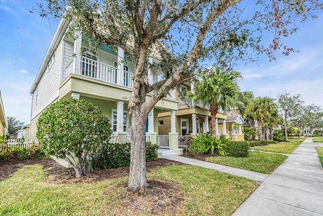 view of front of property with a porch, a balcony, and a front lawn