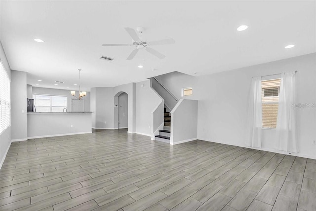 unfurnished living room with ceiling fan with notable chandelier