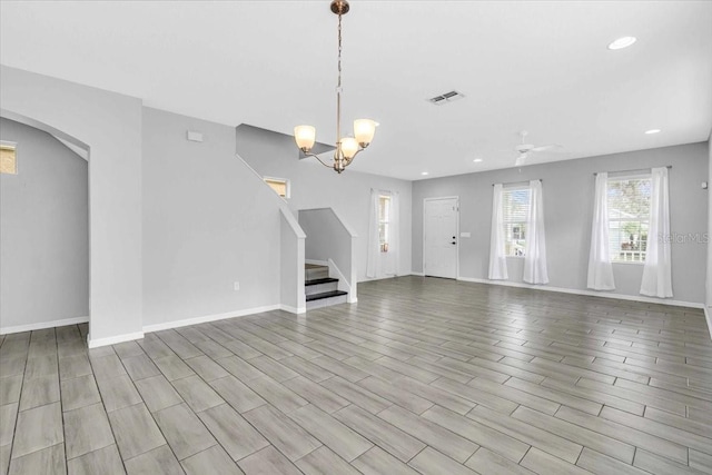 unfurnished living room with ceiling fan with notable chandelier