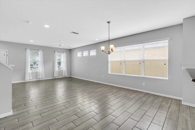 unfurnished living room with ceiling fan with notable chandelier