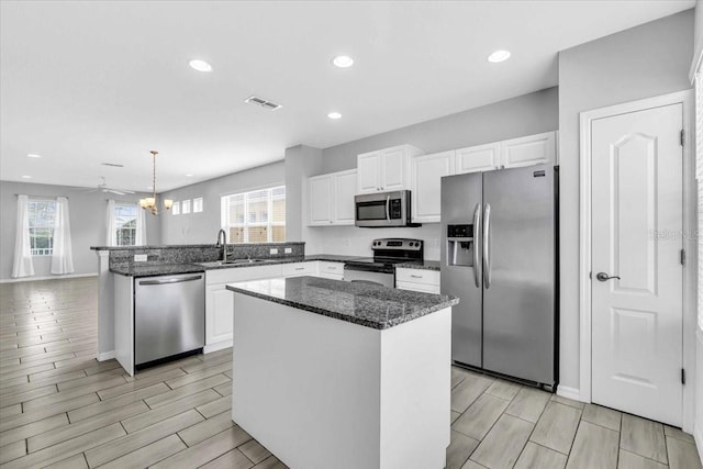 kitchen featuring hanging light fixtures, ceiling fan, a center island, and stainless steel appliances