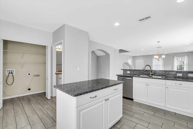 kitchen featuring a center island, dishwasher, sink, dark stone countertops, and white cabinets