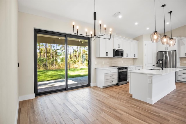 kitchen featuring a kitchen island with sink, stainless steel appliances, decorative backsplash, white cabinets, and decorative light fixtures