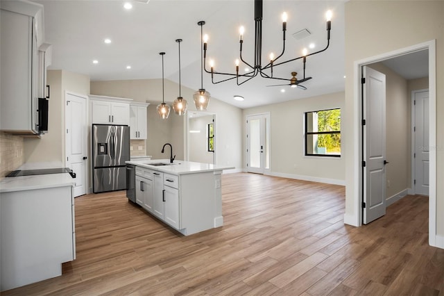 kitchen with a kitchen island with sink, stainless steel appliances, pendant lighting, decorative backsplash, and white cabinetry