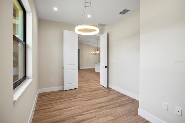 empty room featuring light hardwood / wood-style floors and an inviting chandelier