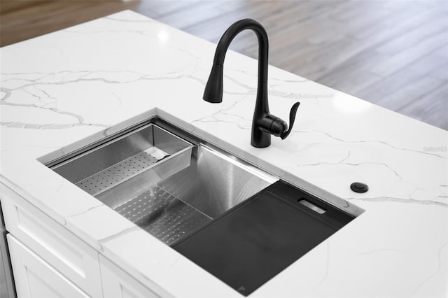 room details with sink, white cabinetry, and light stone counters