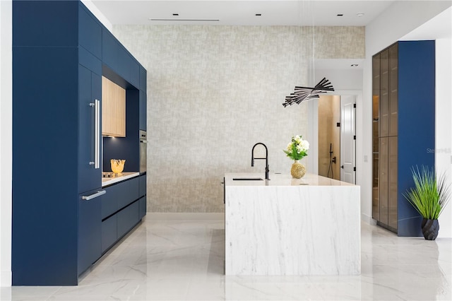 kitchen with sink, blue cabinetry, and an island with sink