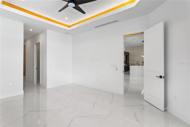 unfurnished room featuring ceiling fan and a raised ceiling