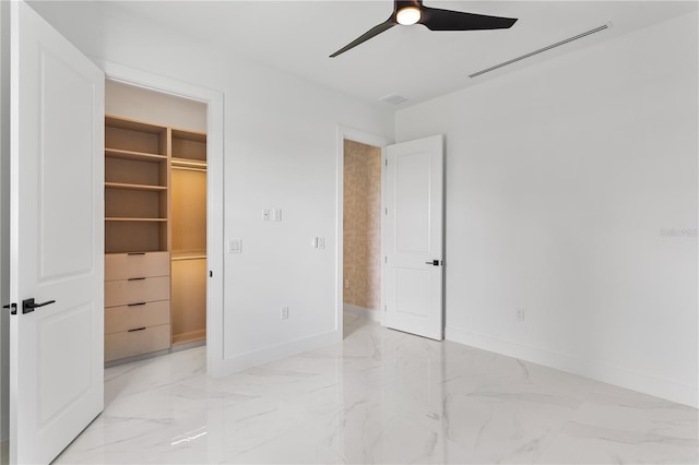 unfurnished bedroom featuring a spacious closet, a closet, and ceiling fan