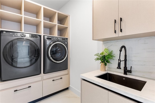 laundry area with sink, washing machine and clothes dryer, and cabinets