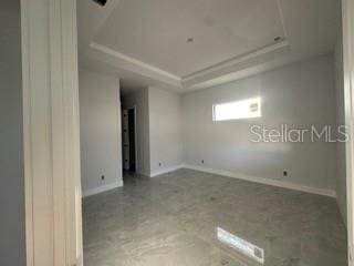 419 NW 4th Ter, Cape Coral, FL 33993 - empty room with a raised ceiling, baseboards, and concrete flooring