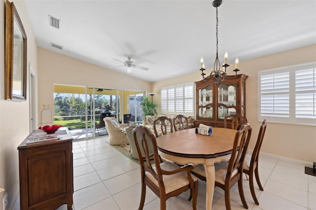 tiled dining area featuring ceiling fan with notable chandelier and lofted ceiling