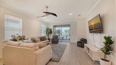 living room featuring a healthy amount of sunlight, light hardwood / wood-style flooring, ceiling fan, and ornamental molding