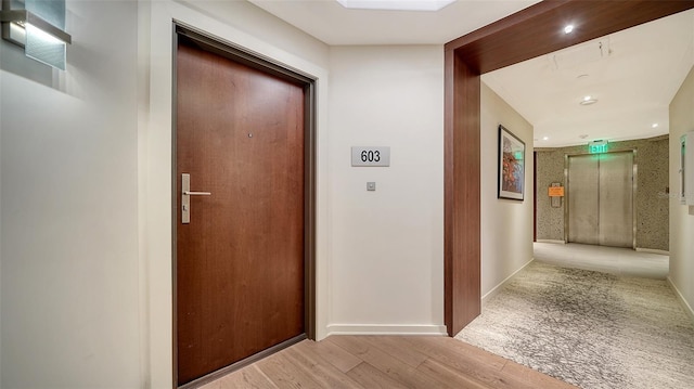 hall with elevator and light hardwood / wood-style floors