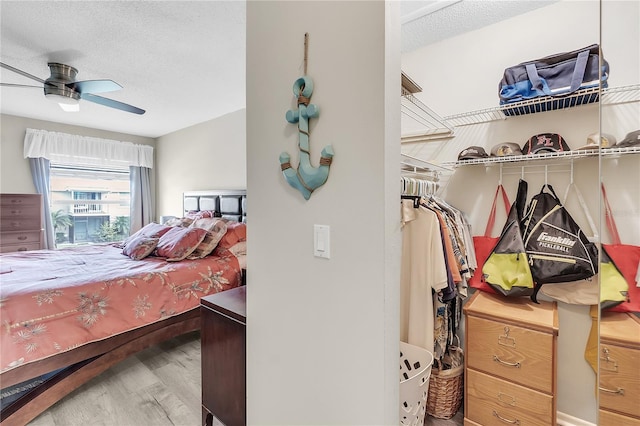 bedroom featuring ceiling fan, hardwood / wood-style floors, and a textured ceiling