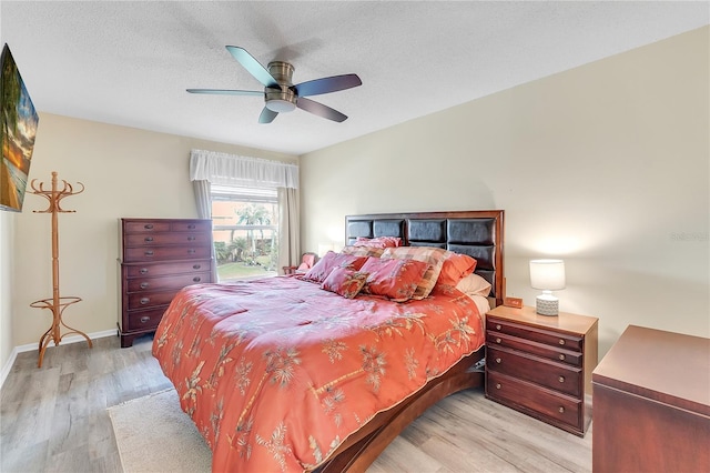 bedroom with ceiling fan, light hardwood / wood-style floors, and a textured ceiling