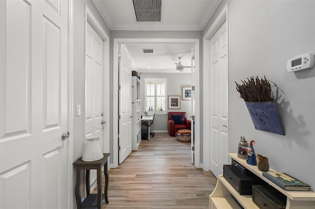 hall with light wood-type flooring and crown molding