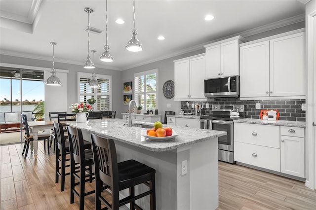 kitchen with white cabinets, stainless steel appliances, and an island with sink