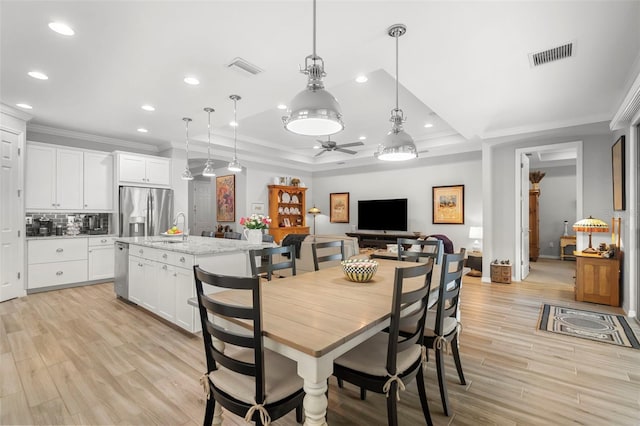 dining space featuring light wood-type flooring, ceiling fan, and crown molding