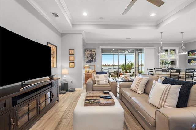 living room with ceiling fan, ornamental molding, a tray ceiling, and light hardwood / wood-style flooring