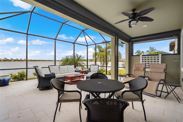 view of patio with an outdoor living space, a water view, glass enclosure, and ceiling fan