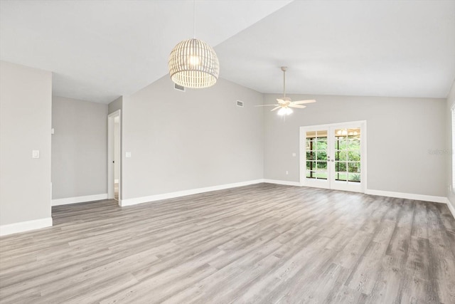 spare room featuring ceiling fan with notable chandelier, french doors, lofted ceiling, and light hardwood / wood-style floors