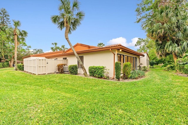 view of side of home featuring a yard and central AC