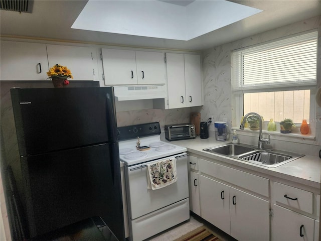 kitchen with black refrigerator, white cabinetry, white range with electric cooktop, and range hood