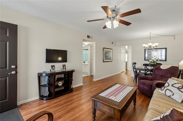 living room with a textured ceiling, ceiling fan with notable chandelier, and wood-type flooring