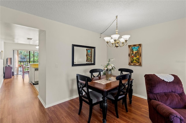 dining area with a textured ceiling, hardwood / wood-style floors, and a chandelier