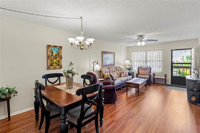 dining space featuring ceiling fan with notable chandelier, hardwood / wood-style flooring, and a textured ceiling