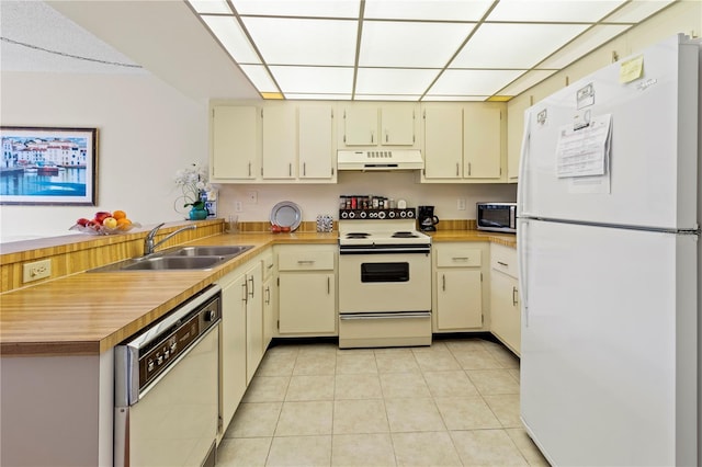 kitchen with white appliances, light tile patterned flooring, cream cabinets, and sink