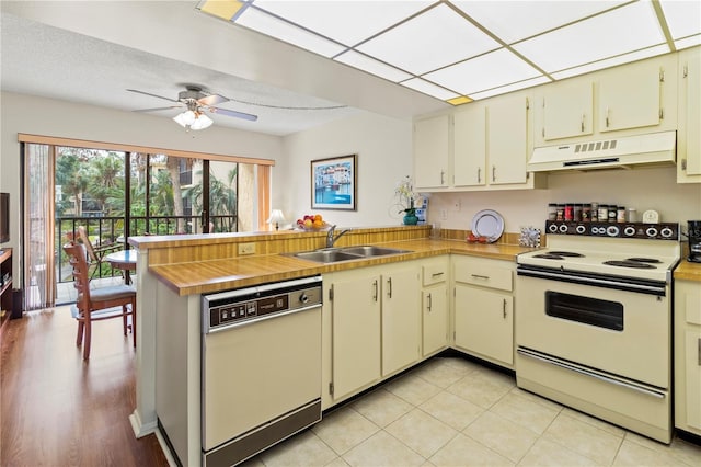 kitchen featuring white appliances, kitchen peninsula, cream cabinetry, and sink