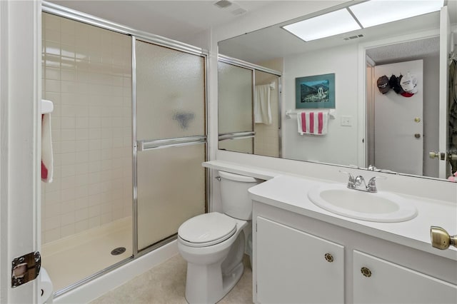 bathroom featuring tile patterned floors, toilet, vanity, and a shower with shower door