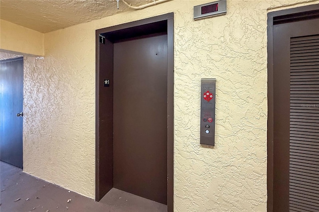 corridor featuring elevator and a textured ceiling