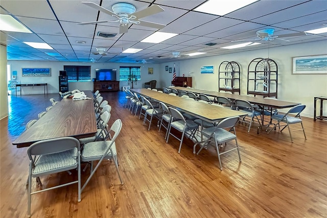 dining space with a drop ceiling, ceiling fan, and hardwood / wood-style floors