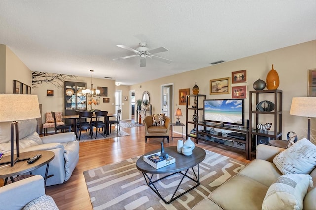 living room with a textured ceiling, ceiling fan with notable chandelier, and hardwood / wood-style flooring